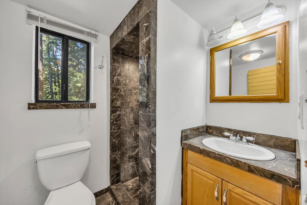 6148 Little Mountain Road Somerset, CA 95684 - Photo 15 of 39 a bathroom with a granite countertop toilet a sink and a mirror