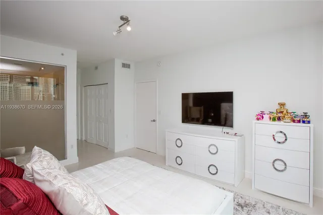 a bedroom with a flat screen tv on the dresser and a flat screen tv