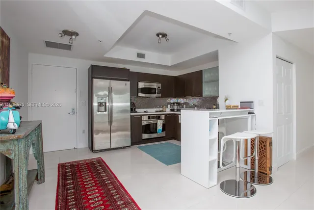 a kitchen with a refrigerator a microwave oven a sink and a dining table