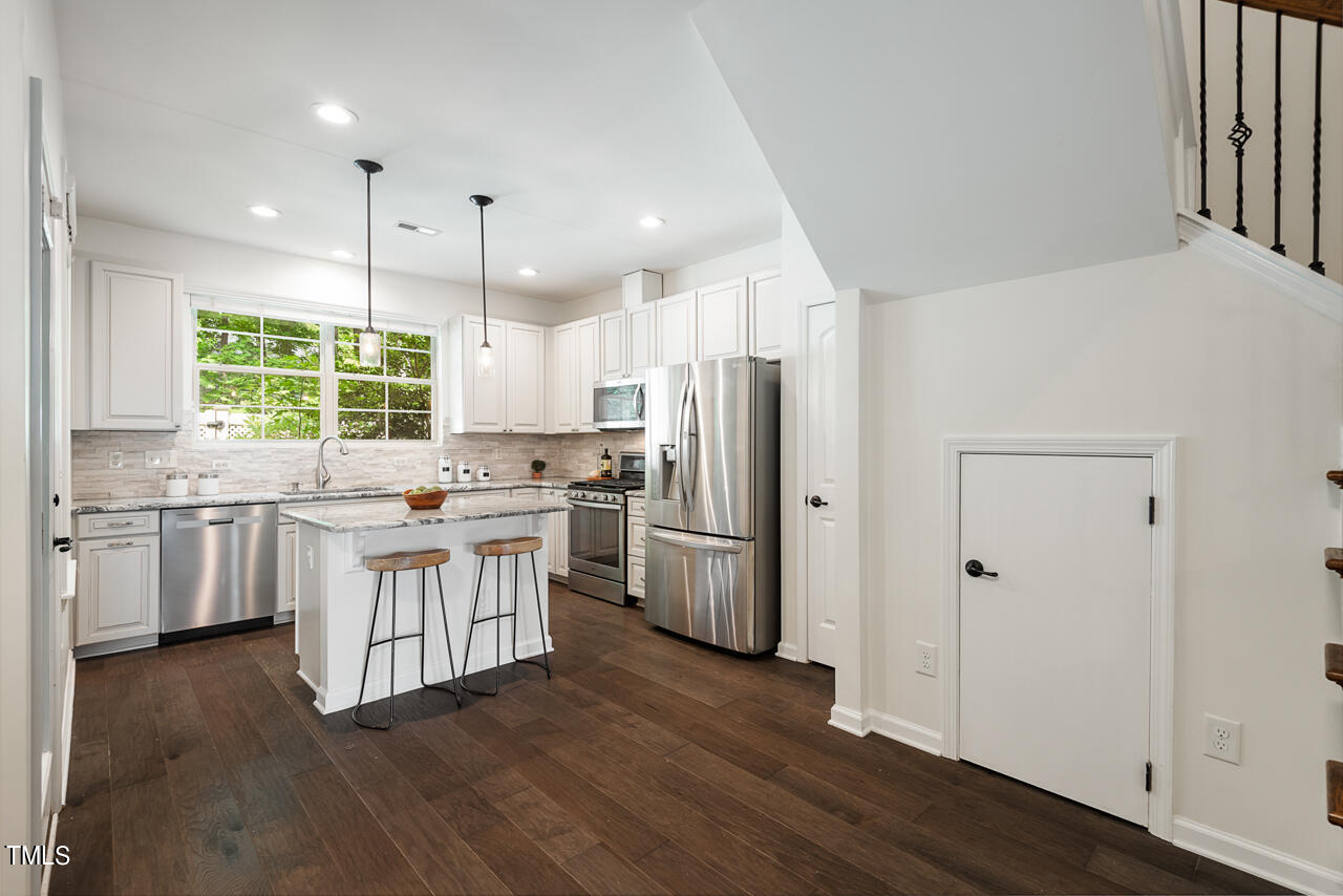 26 Intuition Circle Durham, NC 27705 - Photo 10 of 42 a kitchen with a refrigerator a sink dishwasher a stove and white cabinets with wooden floor