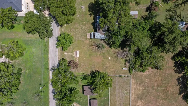 an aerial view of a residential houses with outdoor space and trees