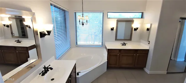 a bathroom with a tub a sink and mirror