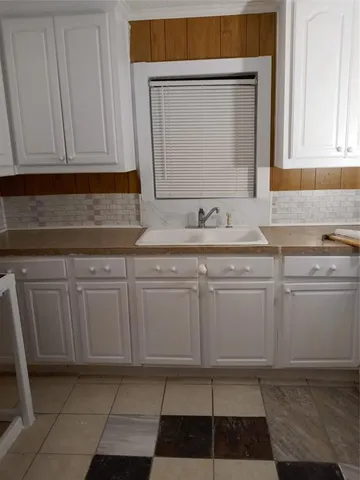 a kitchen with white cabinets a sink and dishwasher