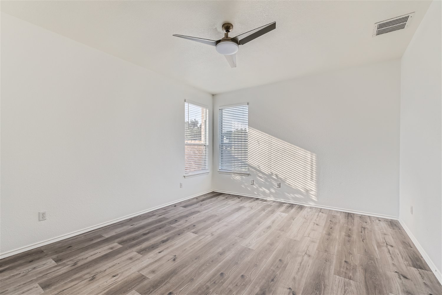 115 Killian Loop Hutto, TX 78634 - Photo 5 of 14 Natural light filters into this bedroom, featuring sleek wood flooring and a modern ceiling fan.