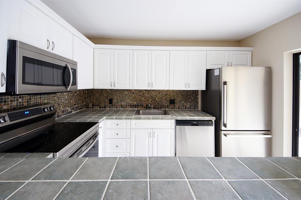 1700 Embassy Drive, Unit 402 West Palm Beach, FL 33401 - Photo 12 of 38 a kitchen with stainless steel appliances granite countertop a refrigerator stove top oven and sink