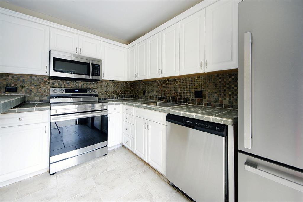 1700 Embassy Drive, Unit 402 West Palm Beach, FL 33401 - Photo 13 of 38 a kitchen with stainless steel appliances white cabinets and a stove a oven with white countertops