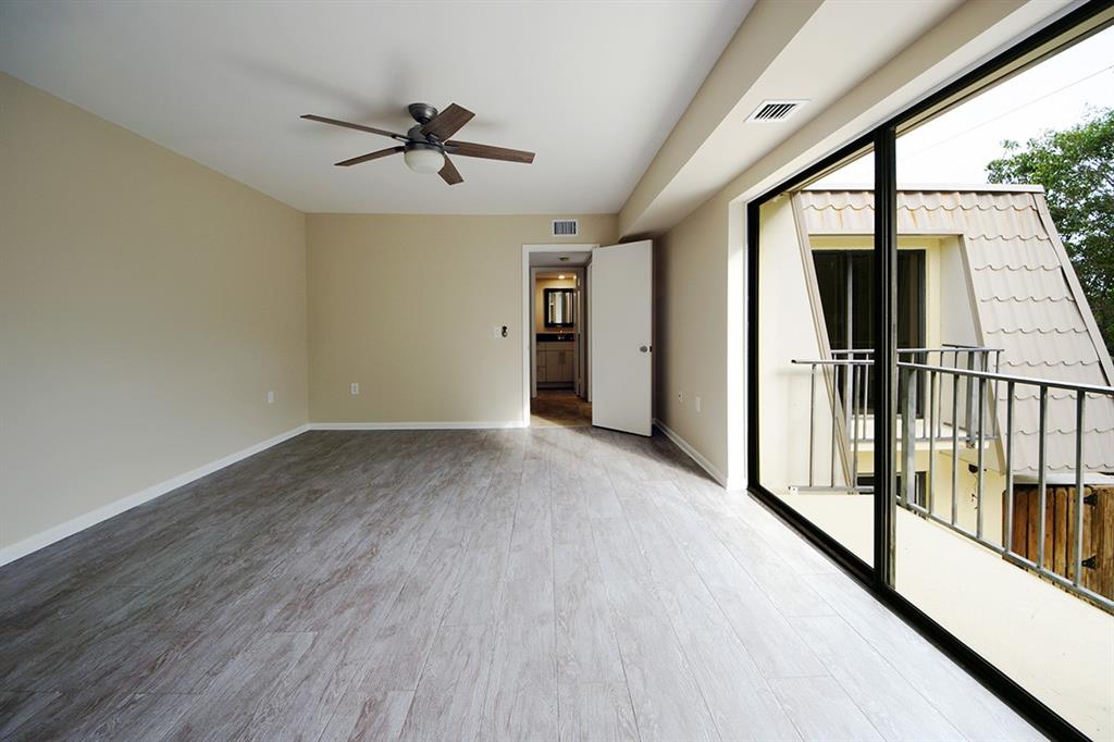 1700 Embassy Drive, Unit 402 West Palm Beach, FL 33401 - Photo 21 of 38 an empty room with wooden floor fan and windows