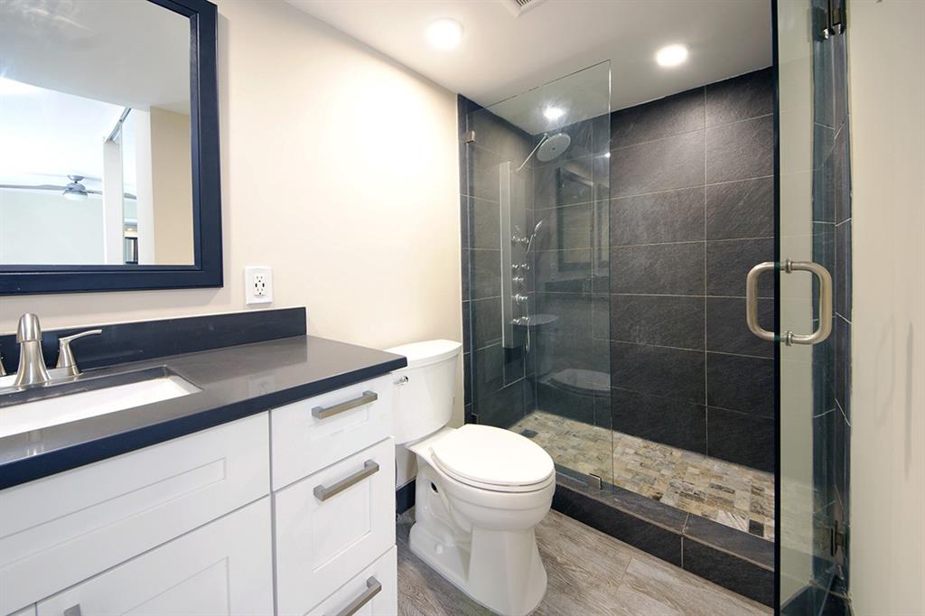 1700 Embassy Drive, Unit 402 West Palm Beach, FL 33401 - Photo 23 of 38 a bathroom with a sink a toilet a mirror and shower