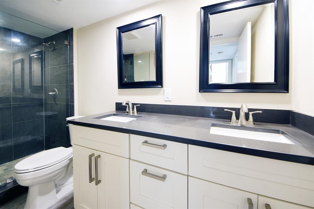 1700 Embassy Drive, Unit 402 West Palm Beach, FL 33401 - Photo 29 of 38 a bathroom with a toilet a sink a vanity a mirror and shower