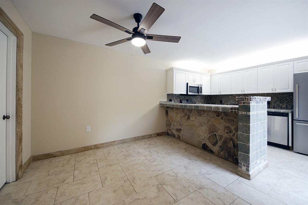 1700 Embassy Drive, Unit 402 West Palm Beach, FL 33401 - Photo 10 of 38 an empty room with a ceiling fan and kitchen view