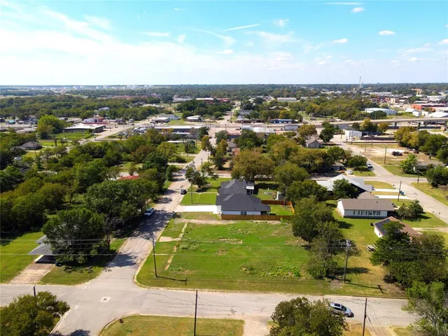 an aerial view of residential houses with outdoor space and trees