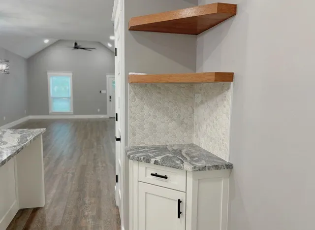 a view of a kitchen with wooden floor and white cabinets