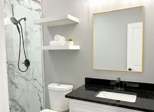 a bathroom with a granite countertop sink a toilet and a mirror