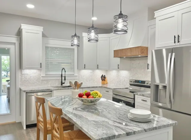 a kitchen with stainless steel appliances granite countertop a sink refrigerator and cabinets