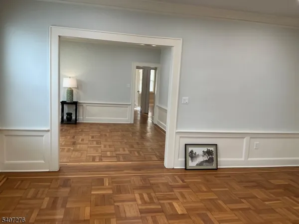 a view of a hallway with wooden floor and a bathroom