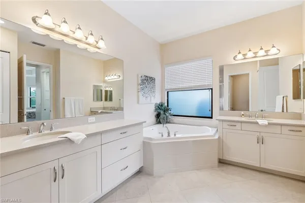 a bathroom with a double vanity sink mirror and bathtub