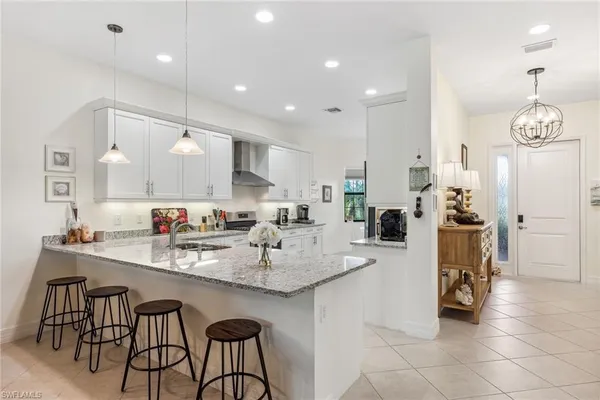 a kitchen with stainless steel appliances kitchen island granite countertop a sink a stove a dining table and chairs