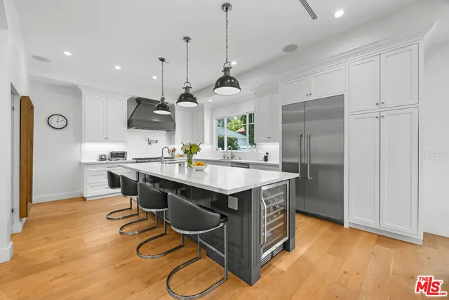 a kitchen with stainless steel appliances granite countertop a sink a stove a refrigerator and island with wooden floor