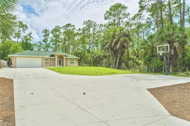 a view of backyard with large trees and wooden fence