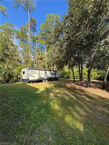 a view of a swimming pool with a yard and large trees