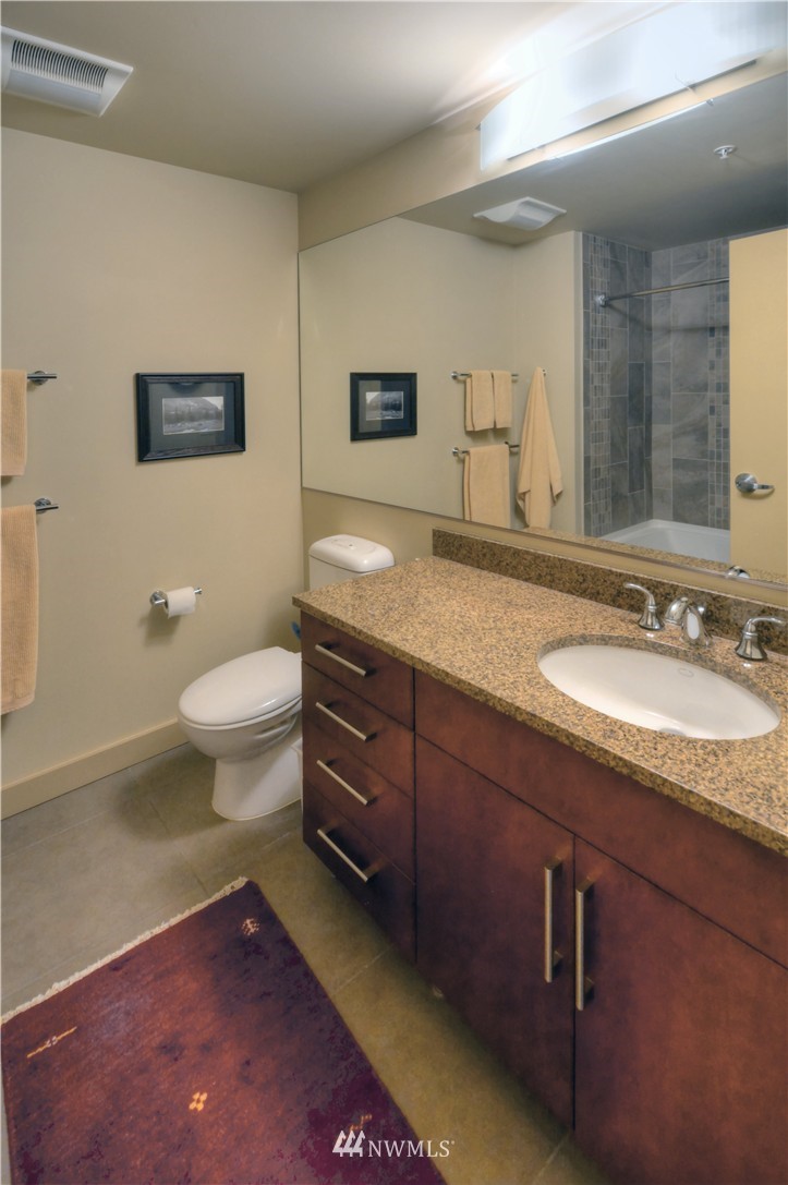 900 Lenora Street, Unit W1105 Seattle, WA 98121 - Photo 14 of 25 a bathroom with a granite countertop sink a toilet and a mirror