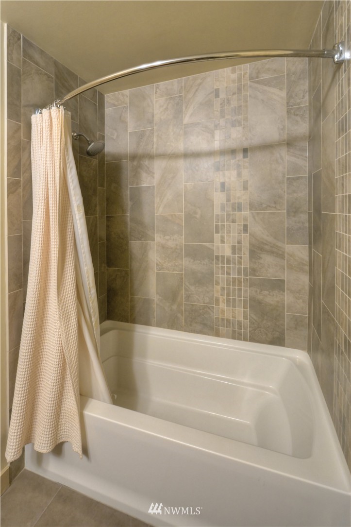 900 Lenora Street, Unit W1105 Seattle, WA 98121 - Photo 15 of 25 a bathroom with a shower curtain and a bath tub