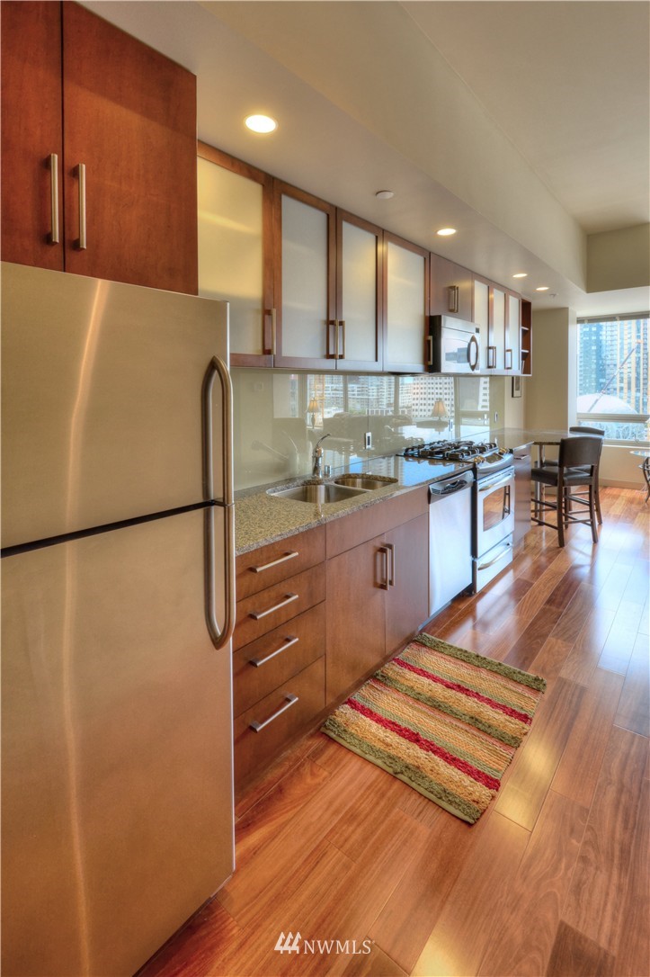900 Lenora Street, Unit W1105 Seattle, WA 98121 - Photo 5 of 25 a kitchen with stainless steel appliances granite countertop a refrigerator and a stove top oven