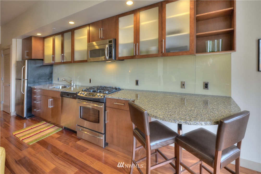 900 Lenora Street, Unit W1105 Seattle, WA 98121 - Photo 6 of 25 a kitchen with stainless steel appliances granite countertop a stove a sink and a microwave