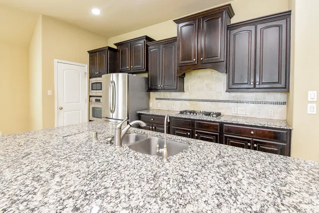 a kitchen with stainless steel appliances granite countertop a refrigerator and a stove top oven