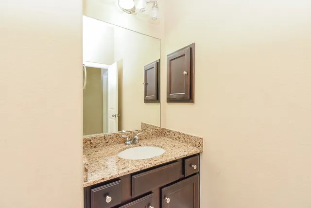 a bathroom with a granite countertop sink and a mirror