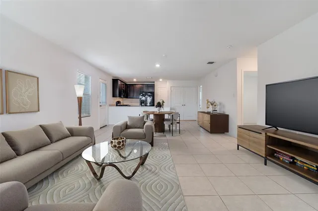 a living room with furniture a flat screen tv and kitchen view