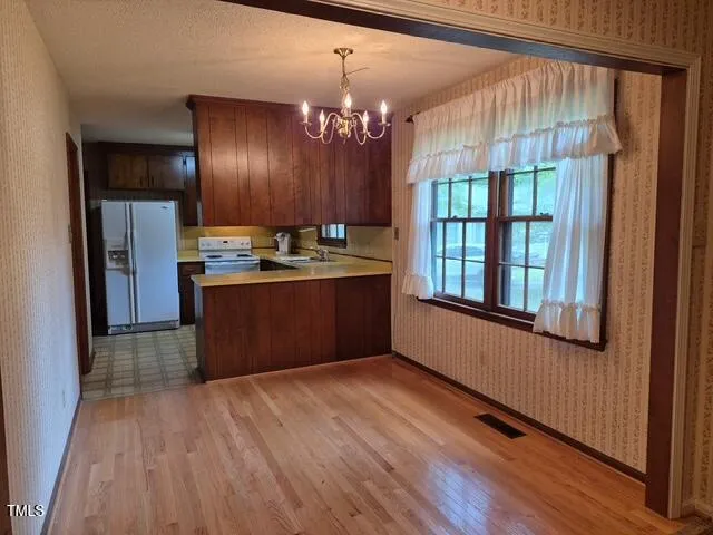 a room with chandelier fan and wooden floor