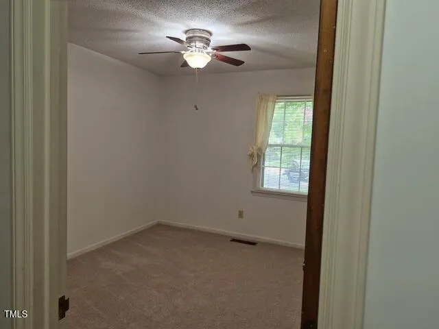 a view of empty room with chandelier fan