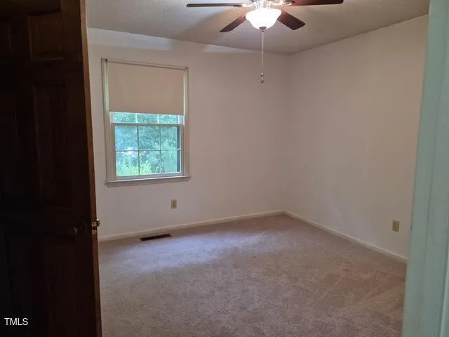 an empty room with a chandelier fan and windows