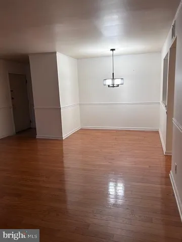 a view of empty room with wooden floor and ceiling fan