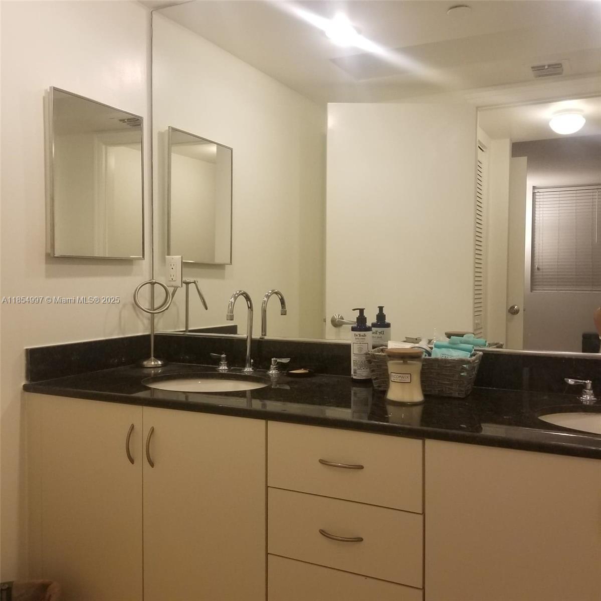 6917 Collins Avenue, Unit 408 Miami Beach, FL 33141 - Photo 19 of 39 a bathroom with double sink and a mirror
