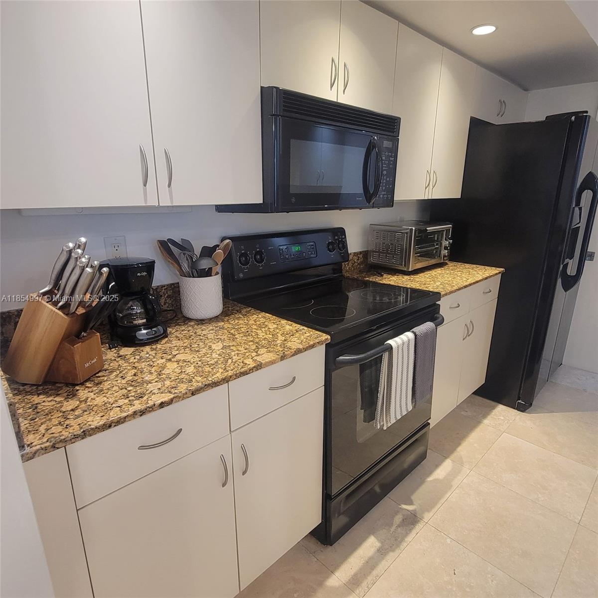 6917 Collins Avenue, Unit 408 Miami Beach, FL 33141 - Photo 4 of 39 a kitchen with granite countertop stainless steel appliances and wooden cabinets