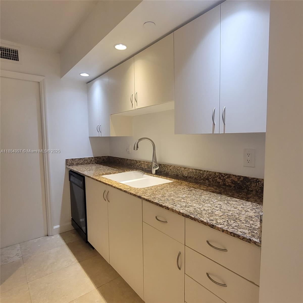 6917 Collins Avenue, Unit 408 Miami Beach, FL 33141 - Photo 5 of 39 a kitchen with granite countertop white cabinets and sink