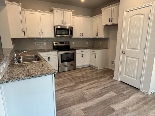 a kitchen with granite countertop white cabinets and stainless steel appliances