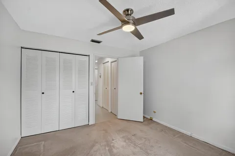 an empty room with chandelier fan and windows