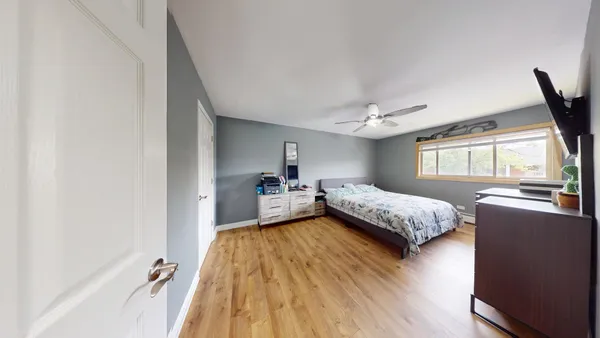 a spacious bedroom with a bed and wooden floor