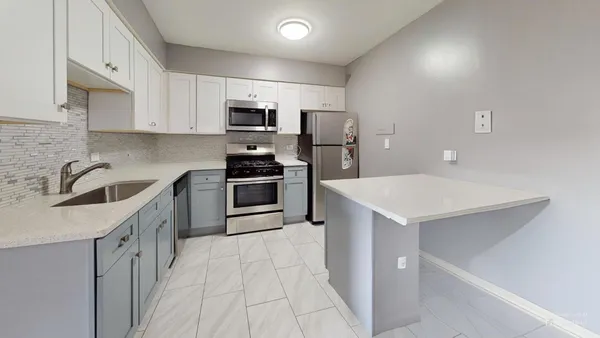 a kitchen with stainless steel appliances a sink a stove a refrigerator a center island and cabinets