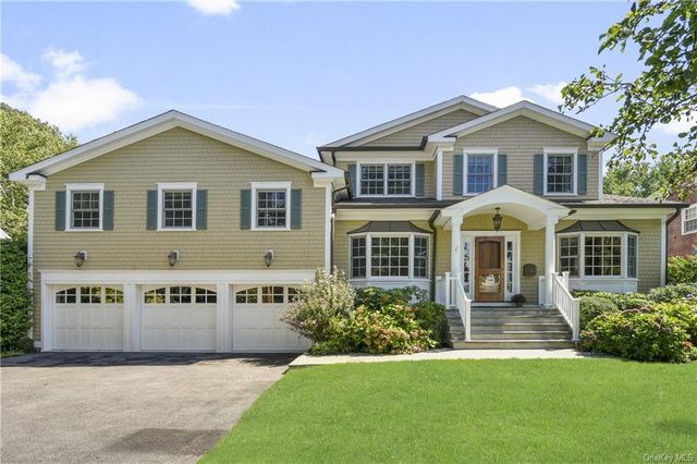 a view of house with garden and tall tress