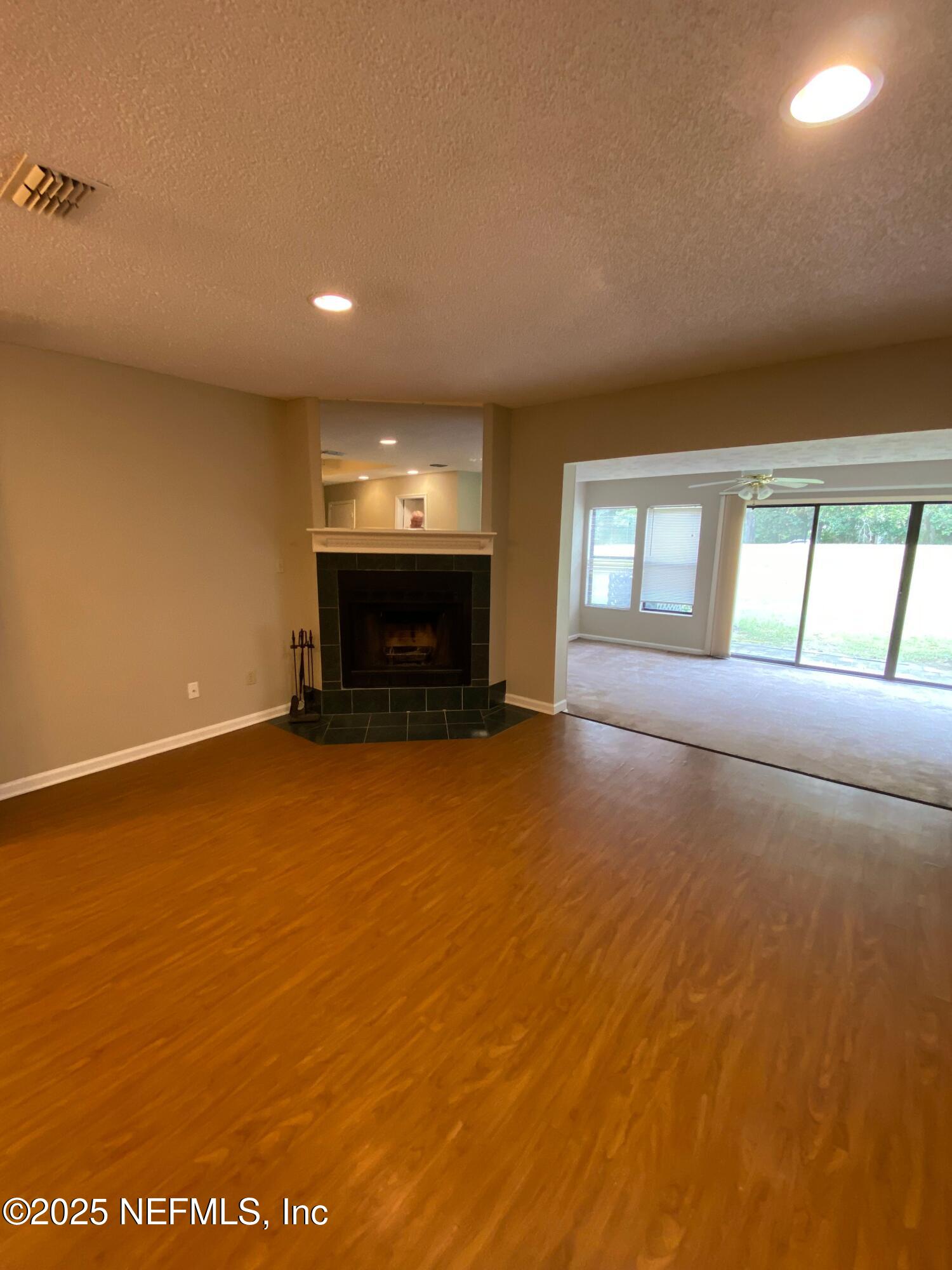 4129 Quiet Creek Loop Middleburg, FL 32068 - Photo 7 of 24 an empty room with windows fireplace and flat screen tv
