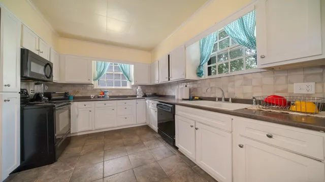 a kitchen with granite countertop white cabinets stainless steel appliances a sink and a window