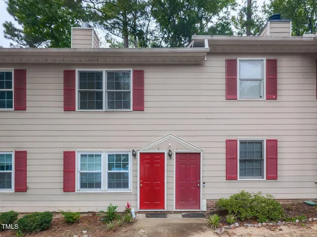 a view of a house with a small yard and a large tree