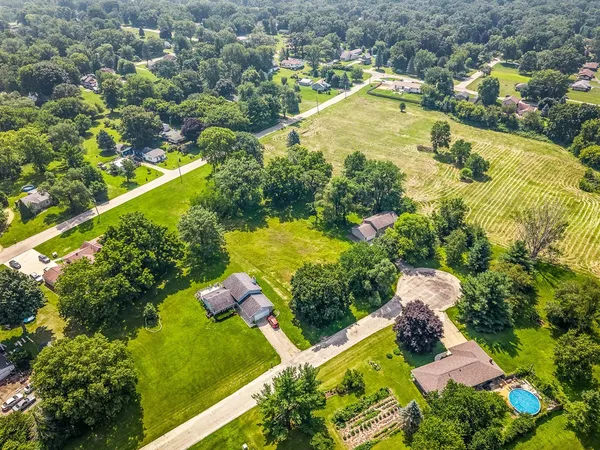 an aerial view of a residential houses with outdoor space and trees all around