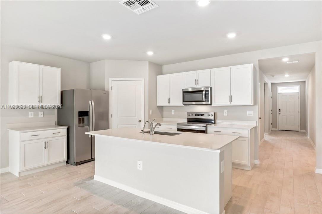 3021 North Lakewood Road LaBelle, FL 33935 - Photo 2 of 13 a kitchen with white cabinets and stainless steel appliances