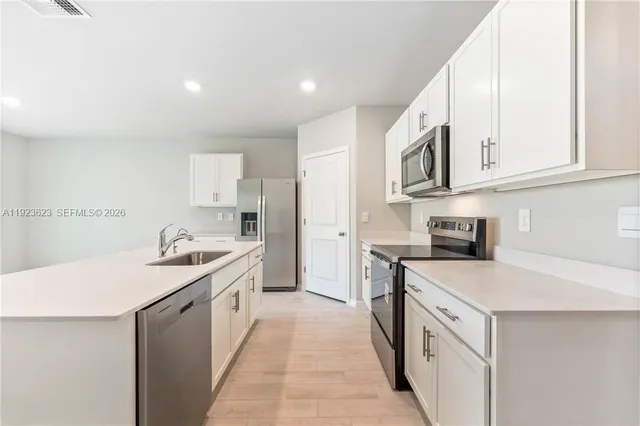 a kitchen with stainless steel appliances granite countertop a sink and dishwasher a stove top oven with white cabinets