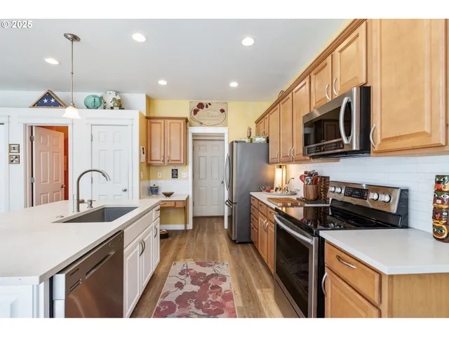 a kitchen with stainless steel appliances a sink a stove a refrigerator a center island and a cabinets